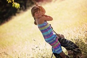 Happy little girl sitting on a swing
