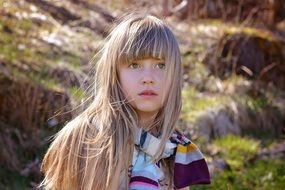 Little girl with long blond hair in a bright scarf