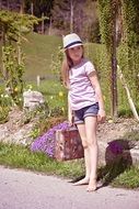 Little girl with luggage waiting in the open air