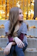 girl sitting on the stairs in the autumn Park