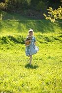 Girl with teddy bear on the meadow in summer