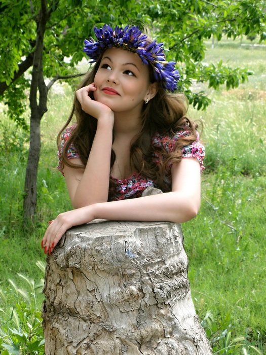 beautiful girl with a wreath of flowers on her head outdoors