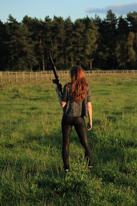 girl with gun on green field