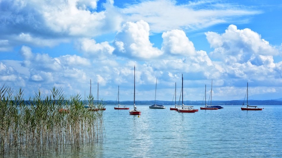anchored sailing boats on chiemsee lake beneath scenic clouds, germany, upper bavaria
