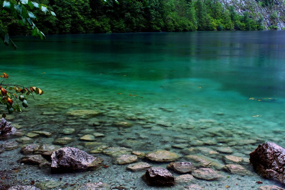 reflection of stones across the blue water of a lake