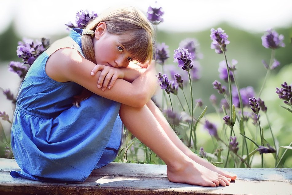 Little girl in a blue dress on a background of flowers