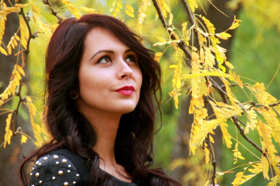 Portrait of woman on the background of a tree with yellow leaves