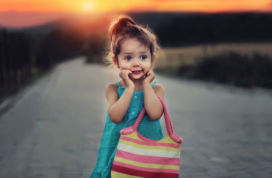 Little beautiful girl on sunset background