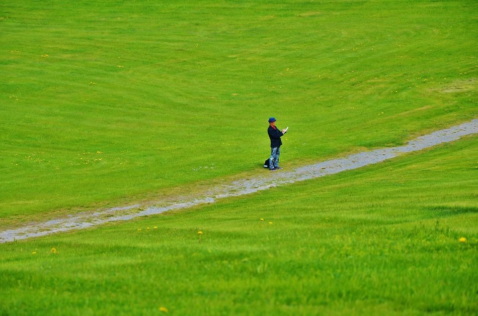 man standing on green grass at road