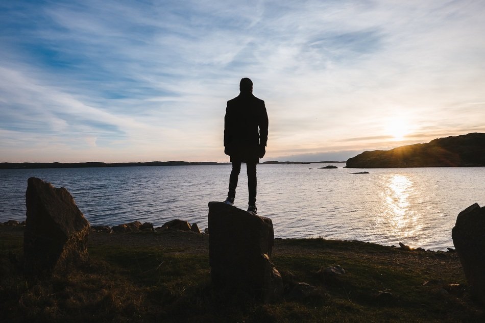 silhouette of a young man on the ocean on the background of the sunrise