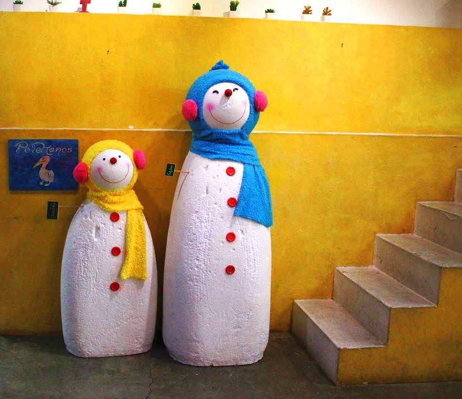 Snowman sculptures near the yellow wall