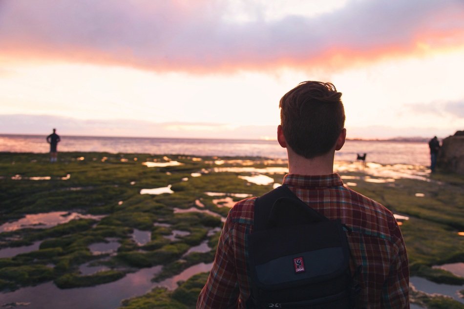 man with a backpack at sunset on the ocean