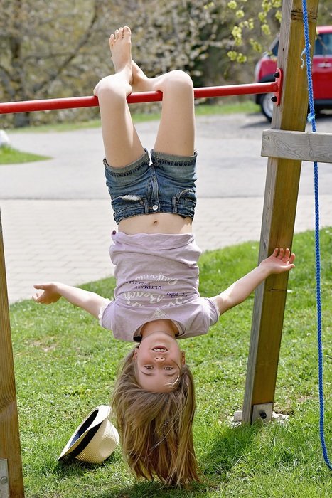 Little girl hanging upside down on a crossbar