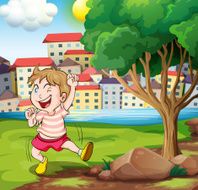 Happy kid near the tree at riverbank beside tall build