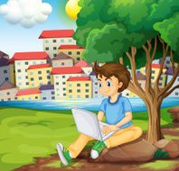 young boy using laptop under tree at riverbank