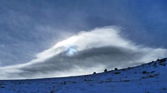 huge white cloud over winter landscape