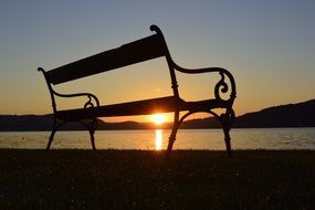 bench near the lake in the rays of the rising sun
