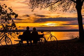 landscape of Couple is sitting near the lake at the sunset time