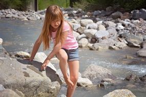 Child among stones on a pond