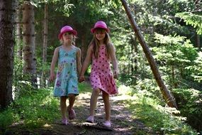 Little girls in pink hats in the middle of the forest