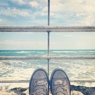 legs of a man near a fence against the background of the sea