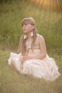 Little girl in a dress in the rays of the evening sun