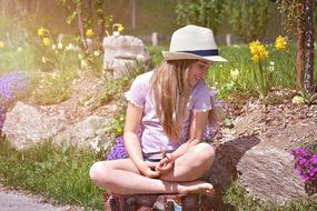 happy barefeet child girl sits on luggage in garden