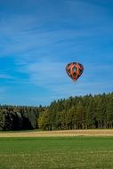 Balloon in the blue sky near the forest