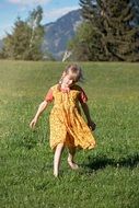 little girl in a dress on a green meadow on a sunny day