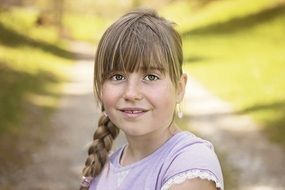 smiling girl with a pigtail in nature