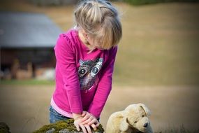 Blonde girl looking at teddy bear