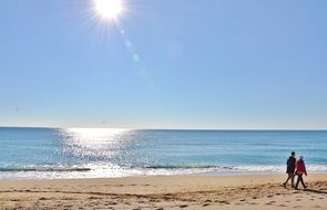 People are walking on the beach near the water