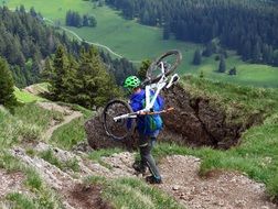 biker with bike on his back at alpine mountain landscape