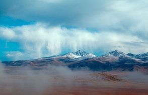 blue sky with clouds on the background of snowy mountains