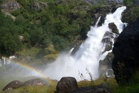 rainbow against the backdrop of a mountain waterfall in Norway