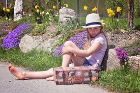 little girl with a suitcase in a picturesque park