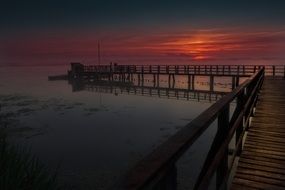 long wooden pier on lake at sunrise, germany, bad buchau