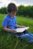 picture of the child is reading a book in a field