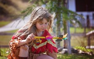 Child in an Indian suit with a tomahawk in the park