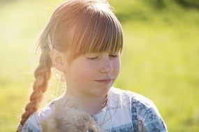 Little girl with a pigtail in the rays of sunlight