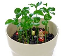 Small figures in a white ceramic pot with green plants