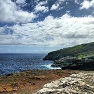 coastline near the ocean under white clouds