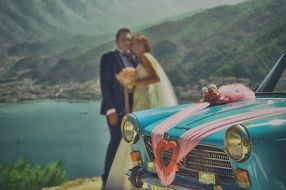 photo of Bride and groom near the retro car