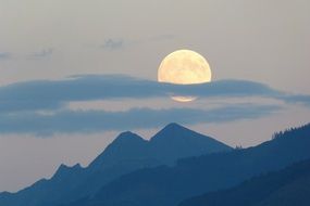 cloud plume at full moon above blue mountains, scenic landscape