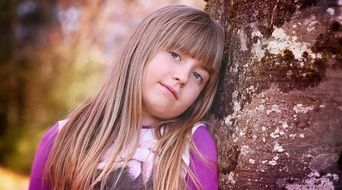 Little girl with long hair near a tree