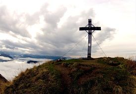 cross on top in the alps on a cloudy day