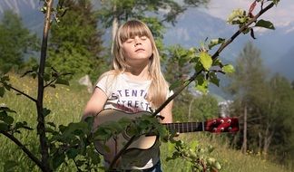little girl playing a guitar in the garden