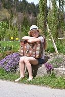 barefoot girl with a suitcase sitting on a stone at the sunlight