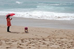 child and a woman with an umbrella on the beach, South Korea