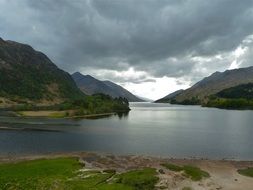 grey clouds above mountain lake at stormy sunset, uk, scotland, glenfinnan